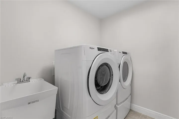 Washroom featuring sink, independent washer and dryer, and light tile patterned floors