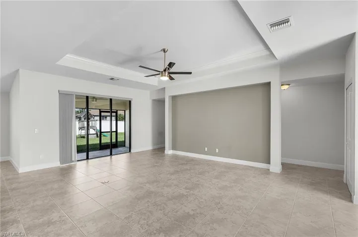 Tiled spare room with ceiling fan and a tray ceiling