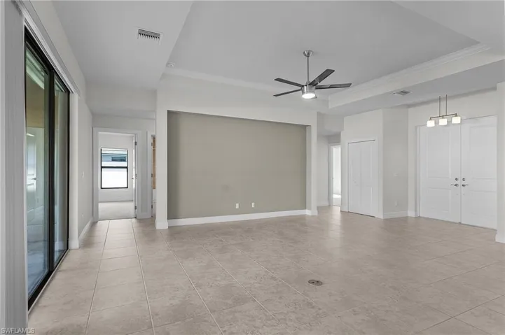 Tiled spare room featuring ornamental molding, ceiling fan, and a raised ceiling