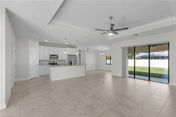 Unfurnished living room featuring a tray ceiling, light tile patterned flooring, and ceiling fan