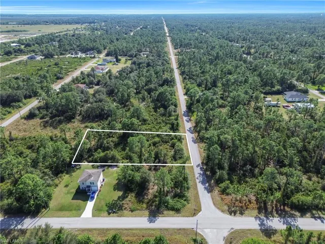 Aerial view of property and surrounding area with a heavily wooded area and property boundaries highlighted