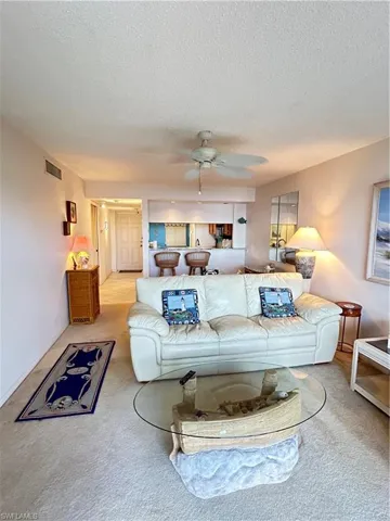 Carpeted living room featuring ceiling fan and a textured ceiling