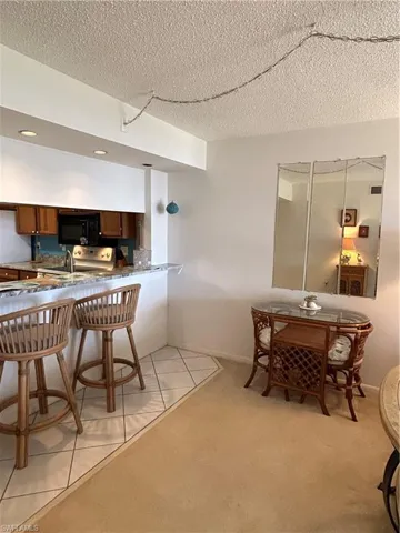 Kitchen featuring kitchen peninsula, a textured ceiling, light colored carpet, and a breakfast bar area