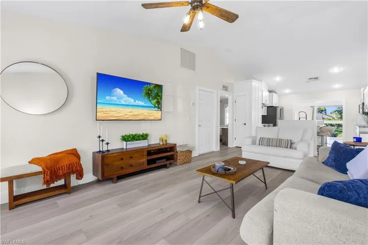 Living room featuring ceiling fan, light wood-type flooring, and vaulted ceiling