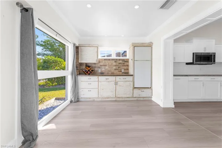 Kitchen featuring light wood-type flooring, tasteful backsplash, plenty of natural light, and crown molding