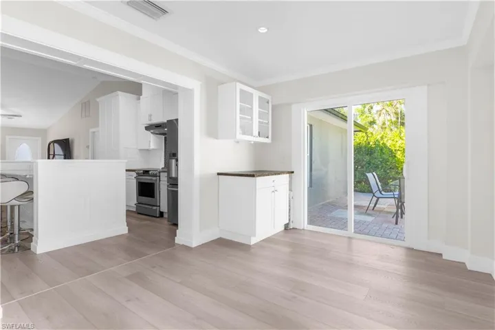 Kitchen featuring lofted ceiling, white cabinets, decorative backsplash, light wood-type flooring, and stainless steel appliances