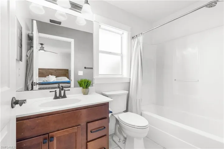 Full bathroom with ceiling fan, toilet, shower / bath combo, and vanity