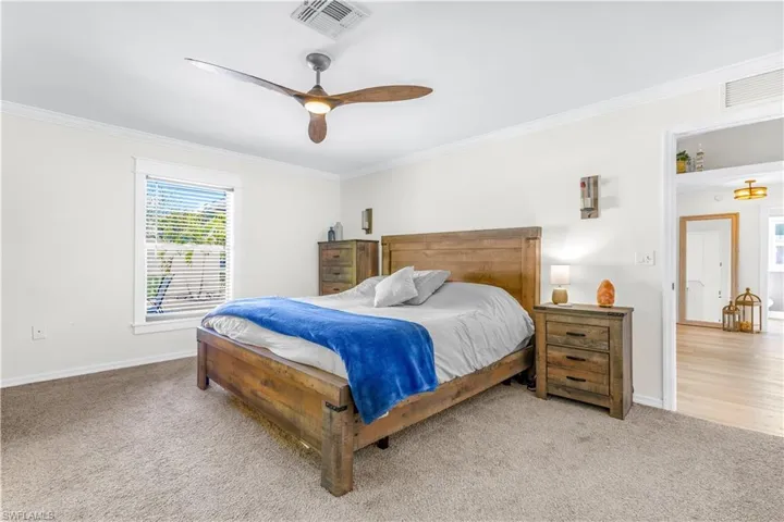 Carpeted bedroom with ceiling fan and ornamental molding