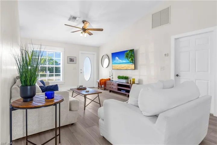 Living room with ceiling fan, light hardwood / wood-style floors, and lofted ceiling
