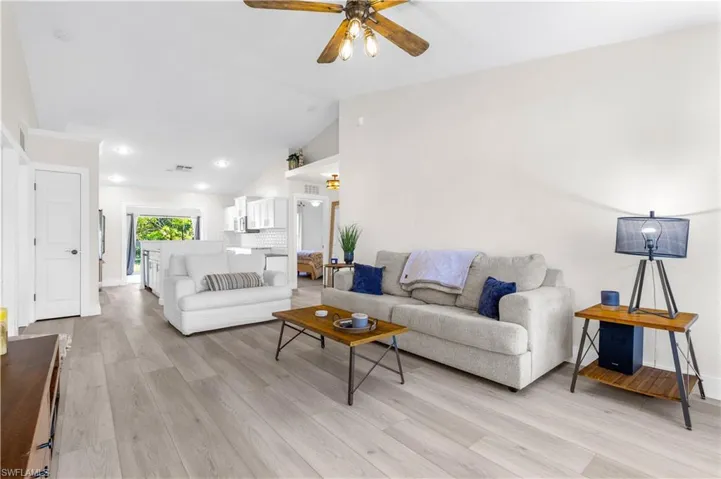 Living room featuring light wood-type flooring, vaulted ceiling, and ceiling fan