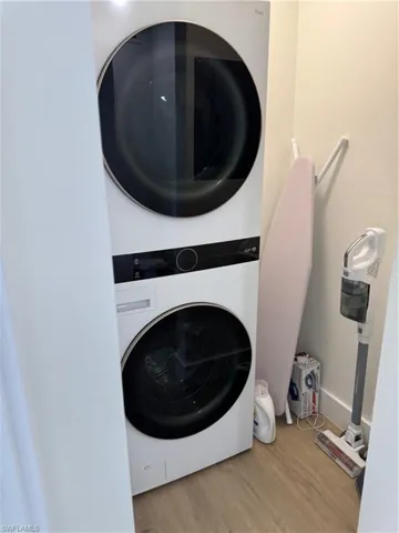 Laundry area with stacked washer / dryer and wood finished floors