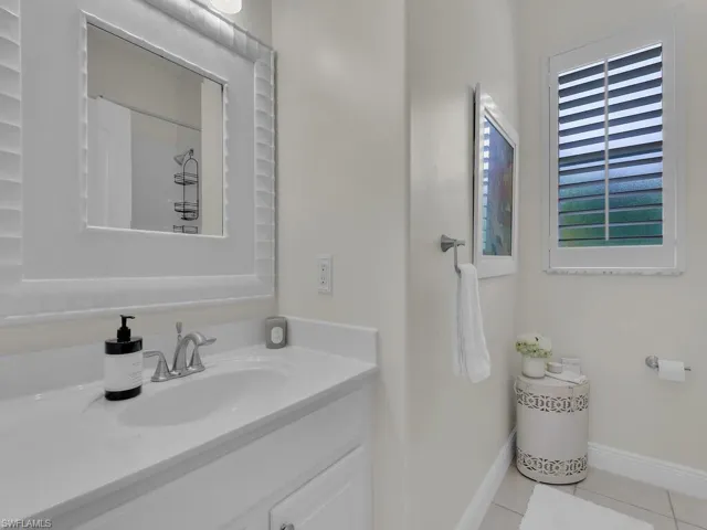 Full bathroom featuring a shower with curtain, vanity, and light tile patterned floors