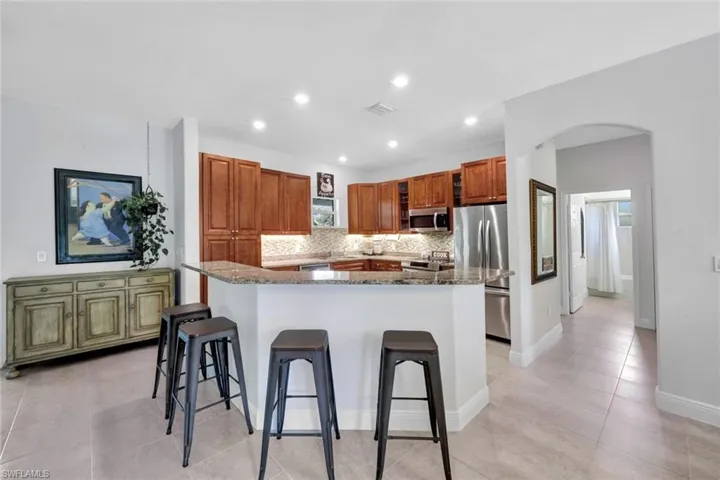 Kitchen with dark stone countertops, a kitchen island, appliances with stainless steel finishes, light tile patterned floors, and backsplash