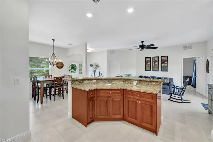 Kitchen featuring ceiling fan with notable chandelier, light stone counters, hanging light fixtures, and light tile patterned floors