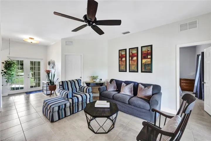 Tiled living room with ceiling fan and french doors