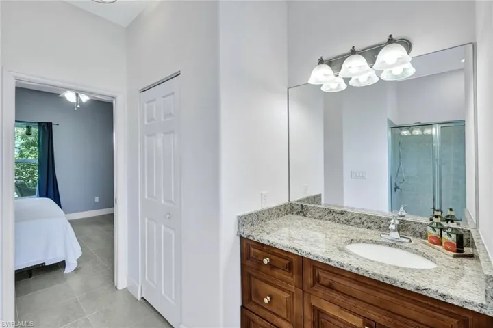 Bathroom with a shower with shower door, vanity, and tile patterned flooring