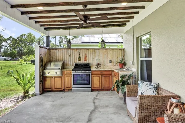 View of patio with area for grilling, sink, ceiling fan, and a grill