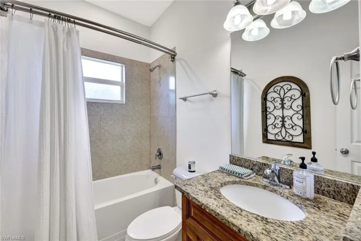 Full bathroom with vanity, shower / bathtub combination with curtain, and toilet