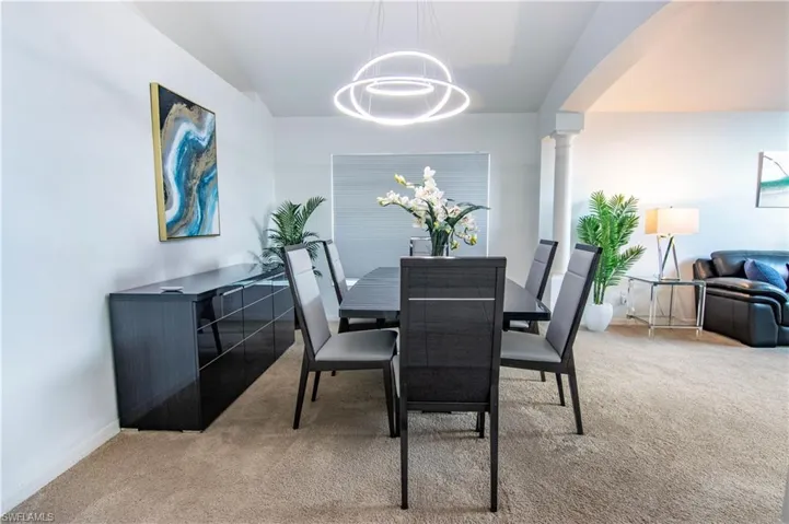 Carpeted dining room with a notable chandelier and ornate columns