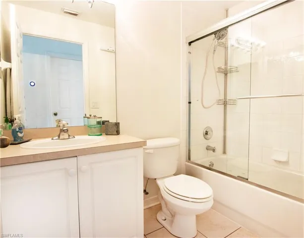 Full bathroom featuring enclosed tub / shower combo, vanity, toilet, and tile floors