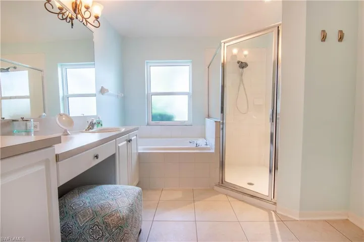 Bathroom featuring plenty of natural light, vanity, tile floors, and plus walk in shower