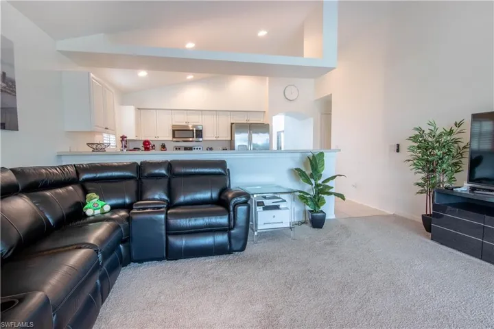 Living room featuring high vaulted ceiling and light carpet