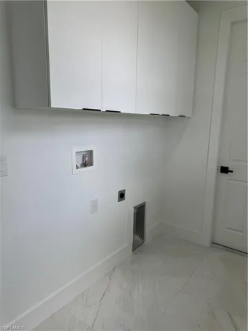 Clothes washing area with hookup for a washing machine, hookup for an electric dryer, light tile flooring, and cabinets