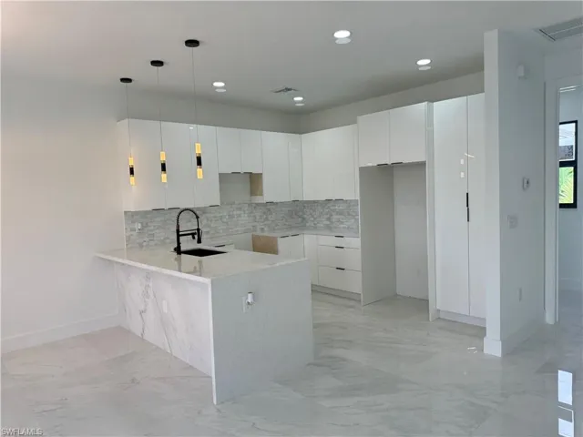 Kitchen featuring sink, white cabinetry, tasteful backsplash, and light tile floors