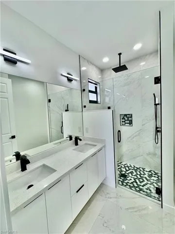 Bathroom with dual vanity, tile flooring, and an enclosed shower