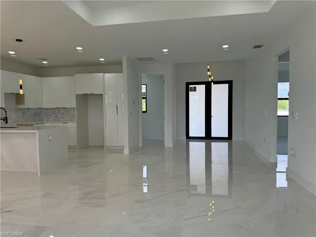 Kitchen featuring backsplash, white cabinetry, a center island, sink, and light tile floors
