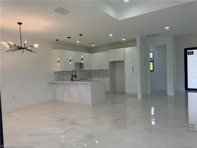 Kitchen featuring white cabinetry, sink, tasteful backsplash, and light tile flooring