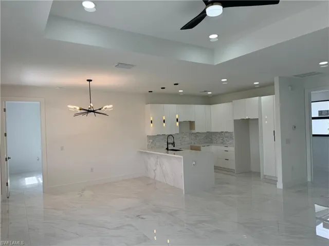 Kitchen featuring white cabinets, backsplash, light tile flooring, and kitchen peninsula