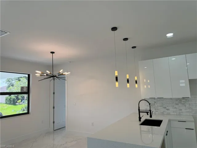Kitchen with hanging light fixtures, an inviting chandelier, sink, and tasteful backsplash