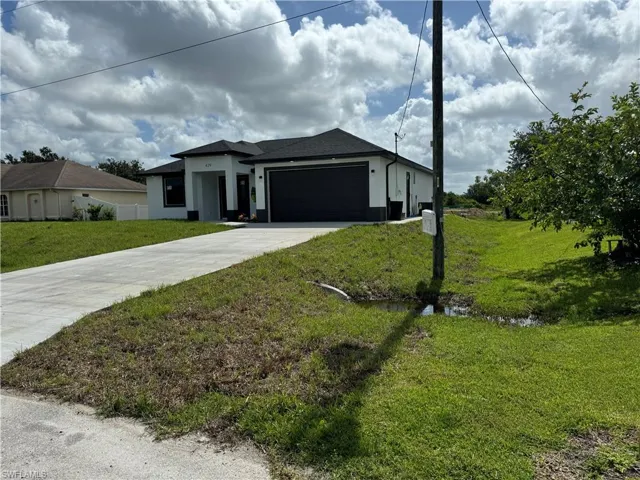 View of front facade featuring a garage and a front yard