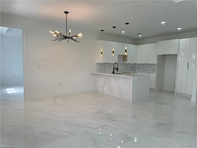 Kitchen with white cabinets, kitchen peninsula, pendant lighting, sink, and light tile flooring