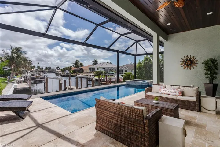 Screened lanai featuring a rectangular swimming pool with an integrated spa, a wood-finish ceiling with recessed lighting and a ceiling fan, and light-colored tile flooring
