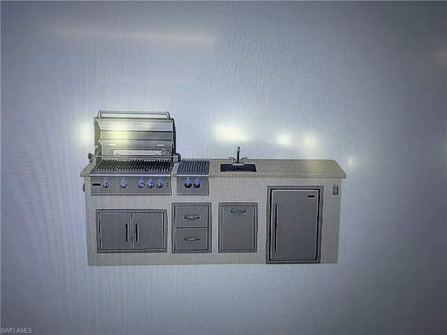Outdoor kitchen island featuring a stainless steel grill, side burner, integrated sink, and under-counter refrigerator