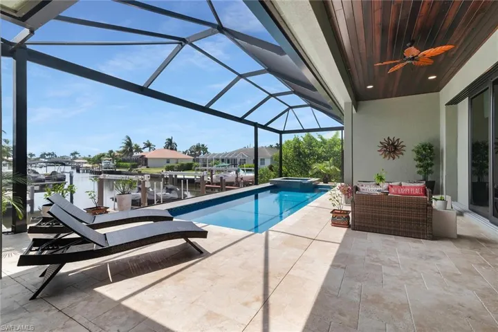 Screened lanai featuring a linear pool, integrated spa, and expansive paved deck