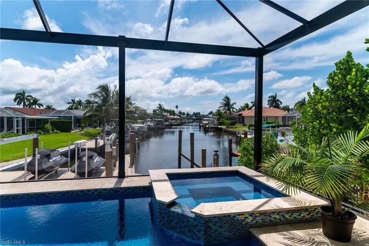 Screened lanai featuring a swimming pool, integrated spa with mosaic tile surround, and direct canal access with a private dock