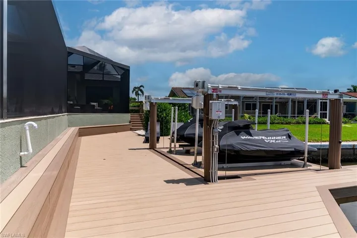 Expansive composite decking featuring a built-in bench, dual boat lifts, and direct canal access