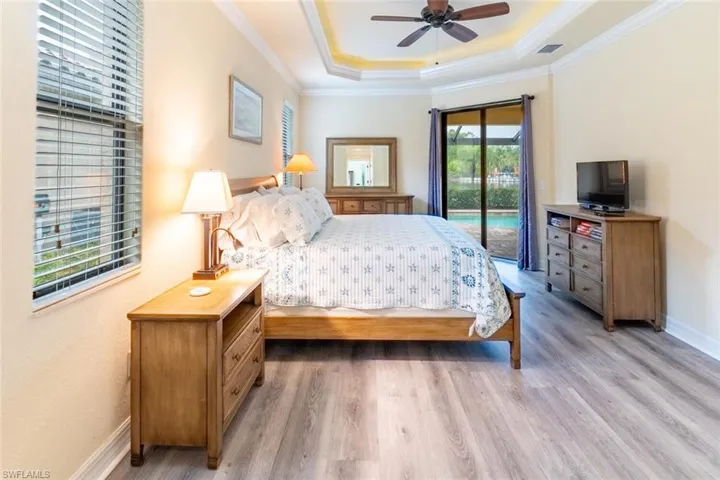 Bedroom with ornamental molding, access to outside, light wood-style flooring, and a raised ceiling