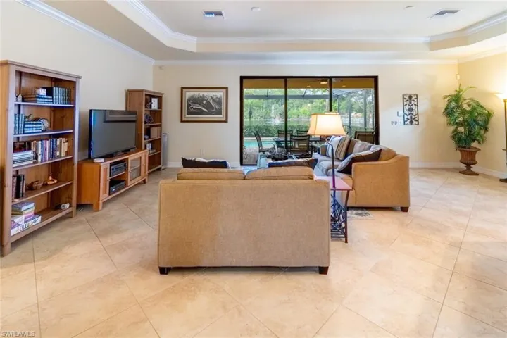 Living area with ornamental molding, visible vents, light tile patterned floors, and a raised ceiling