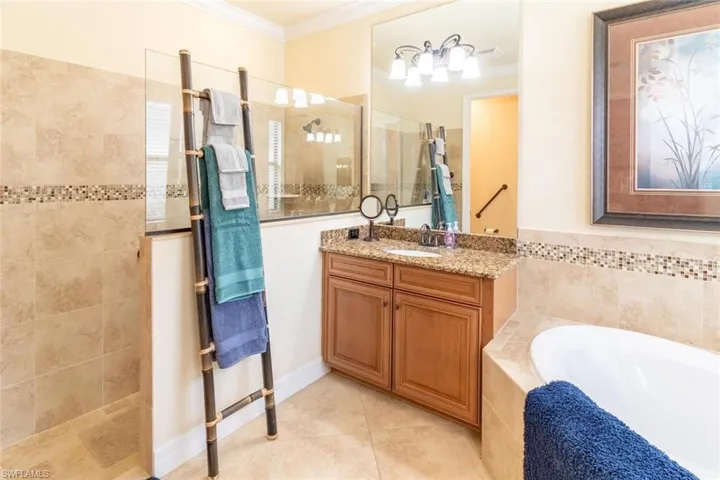 Bathroom with tile patterned floors, a bath, vanity, ornamental molding, and a walk in shower
