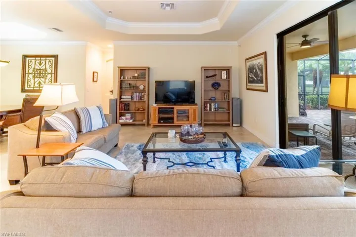 Living room with a ceiling fan, crown molding, a tray ceiling, and visible vents