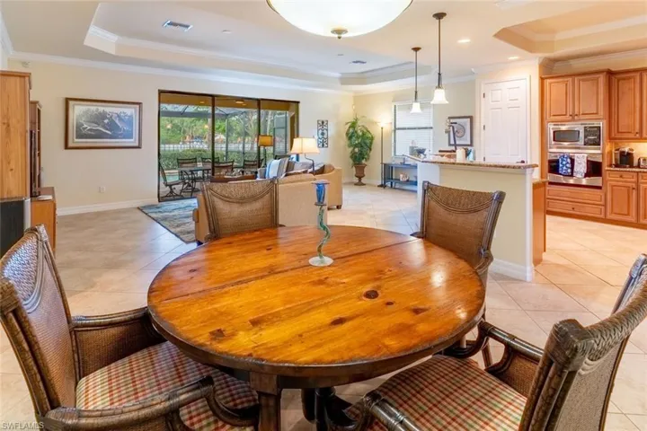 Dining space featuring light tile patterned floors, a raised ceiling, baseboards, ornamental molding, and visible vents