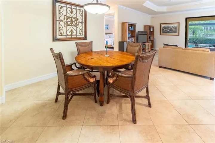 Dining room featuring a raised ceiling, baseboards, crown molding, and light tile patterned floors