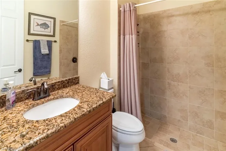 Full bathroom with tiled shower, vanity, and toilet