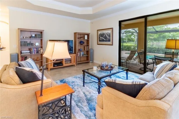 Tiled living room with baseboards, a raised ceiling, and crown molding