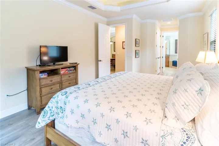 Bedroom featuring baseboards, ornamental molding, and light wood finished floors
