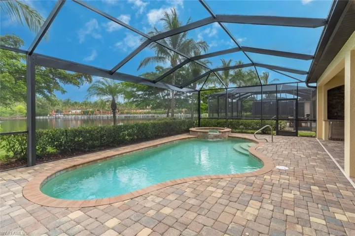 View of swimming pool featuring a lanai, a water view, a patio area, and a pool with connected hot tub